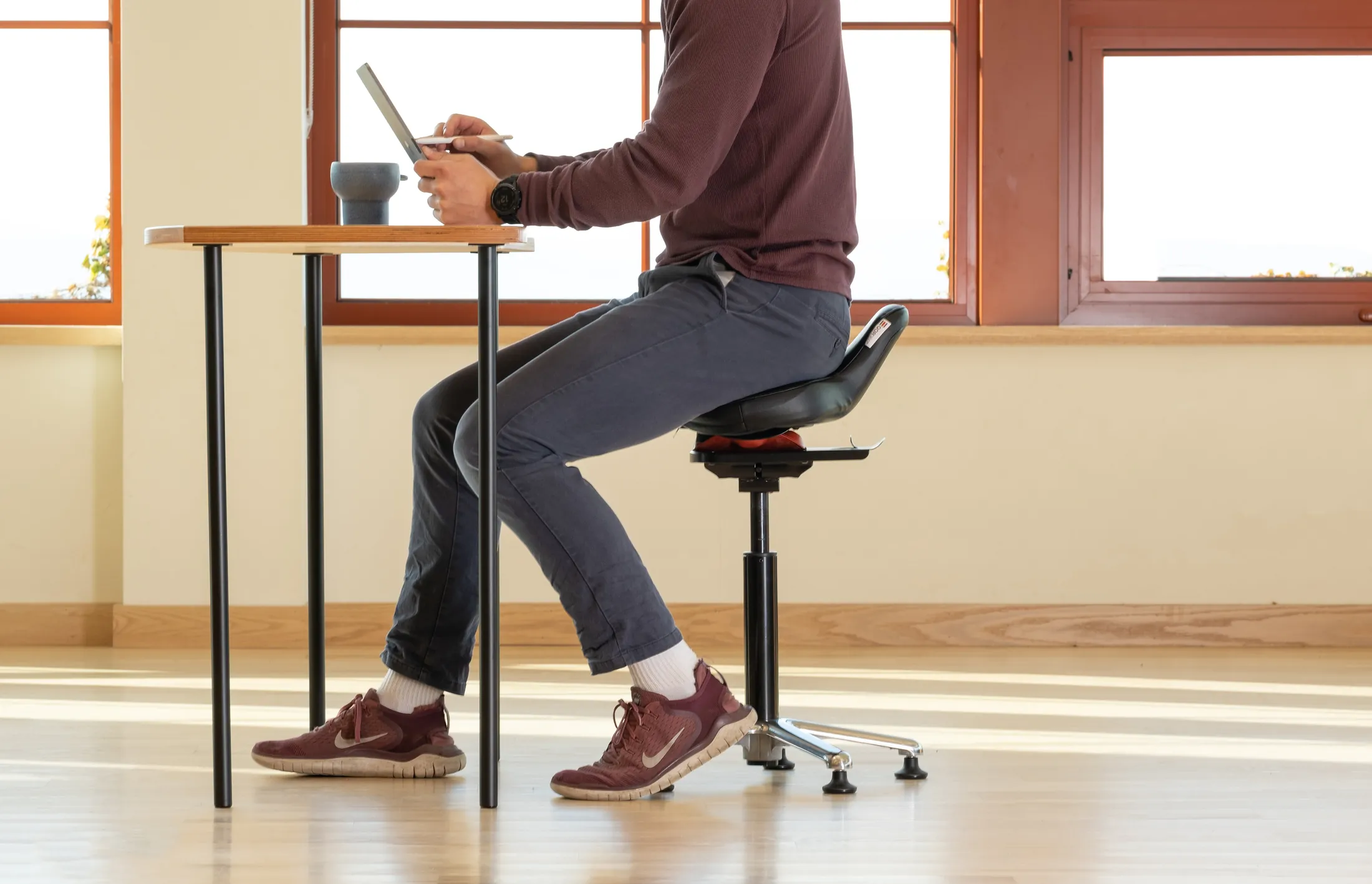 Person working at a desk on the black Ariel 2.0 in an active sitting posture