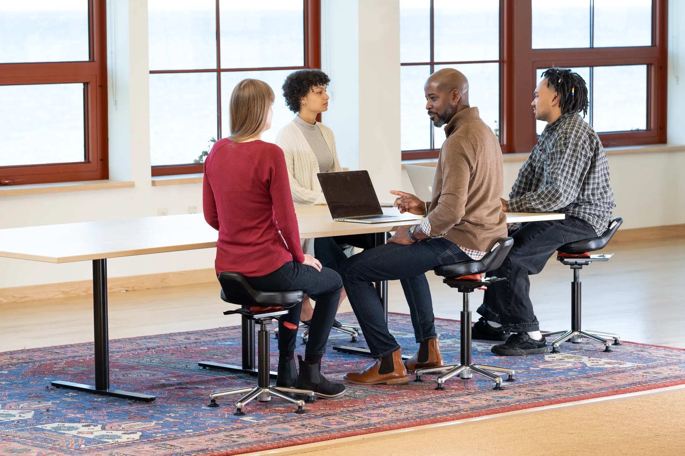 Four people meeting at a conference table, seated on black Ariel 2.0 chairs